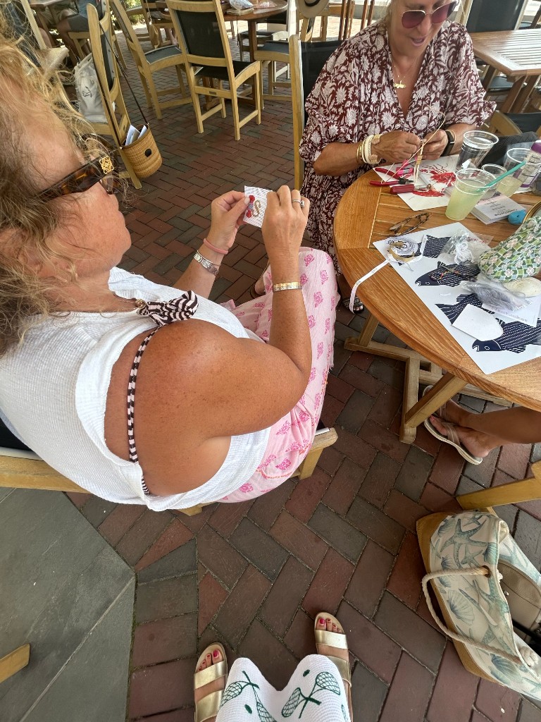 Friends stitching needlepoint together at an outdoor table