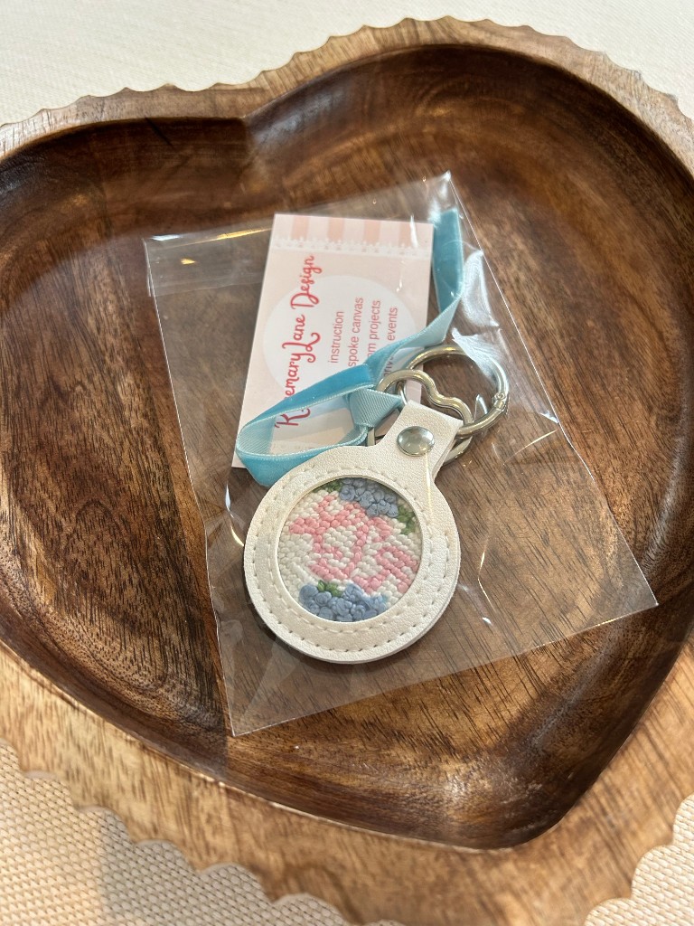 A finished floral needlepoint key fob, packed with a ribbon and a studio card