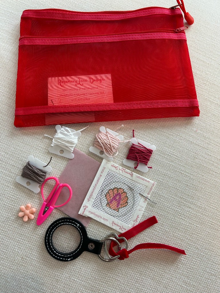 A Rosemary Lane project pouch with threads, scissors, a shell canvas, and a key fob finding