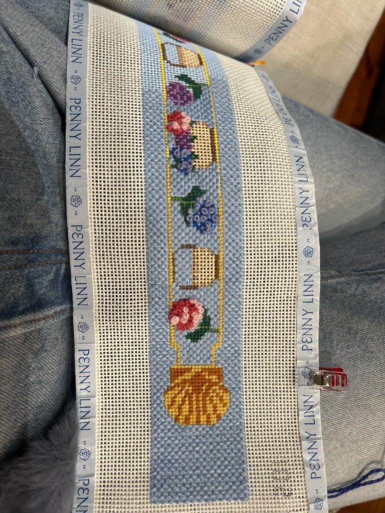 A needlepoint belt with baskets, shells, and flowers